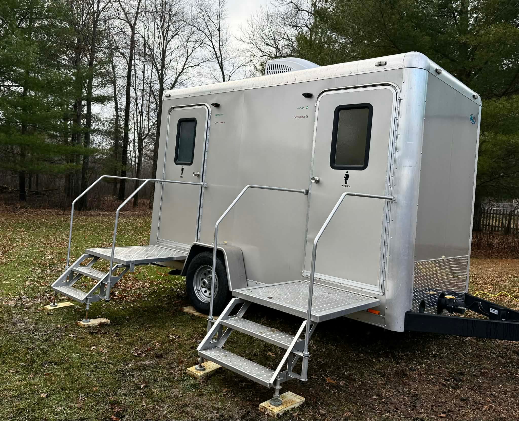 Two-stall Porcelain & Silk restroom trailer set on a wooded property